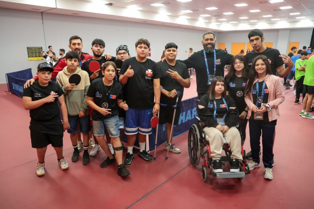 Fotografía grupal de un grupo de jóvenes deportistas con discapacidad junto con su equipo de entrenadores en el Centro de Entrenamiento Paralímpico, todos vestidos con polera negra. 