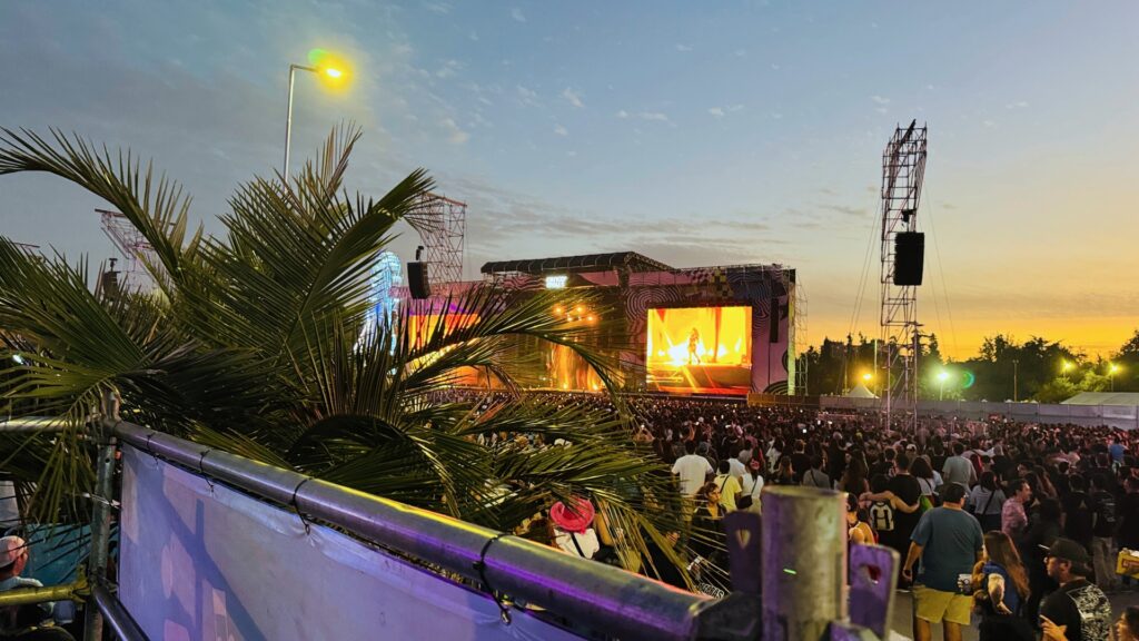 Fotografía de la vista al escenario Cenco Malls desde la tarima accesible correspondiente, en la esquina izquierda están las hojas de la palmera que obstruye la vista.