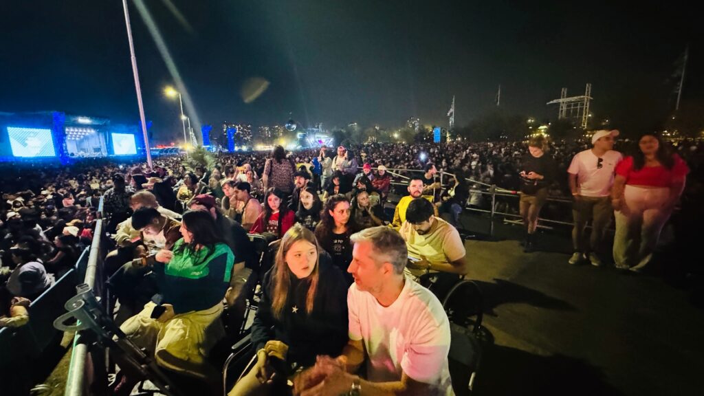 Fotografía panorámica de la tarima Cenco Malls de noche, llena de personas y con el escenario del Banco de Chile de fondo.